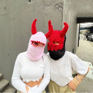 Detail of pink and red hand-knitted devil horn balaclavas with cozy wool texture