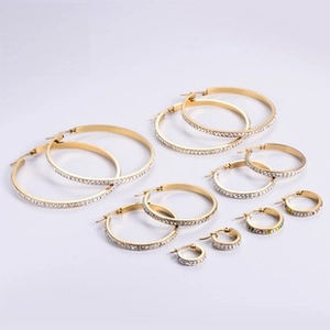 Detalle de pendientes de aro bañados en oro de 18K con pedrería en varios tamaños