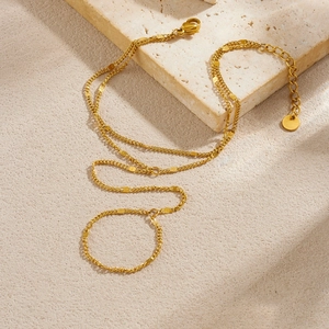 Layered 18k gold plated stainless steel hand chain ring bracelet on a stone surface