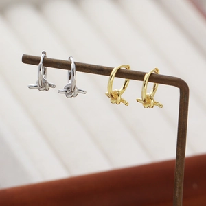 Detail of silver and gold knotted hoop earrings displayed on a professional jewelry stand