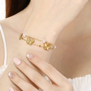 Elegant gold double-layered butterfly and pearl stainless steel bracelet on a female wrist
