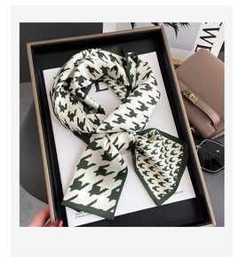 Close-up of knotted dark green houndstooth silk scarf on a black display tray