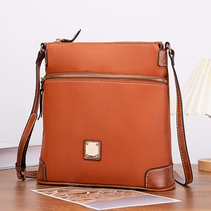 Detail of tan pebble leather crossbody bag with metal plaque and white contrast stitching
