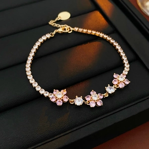 Macro detail of gold flower bracelet with pink and white crystals on black leather
