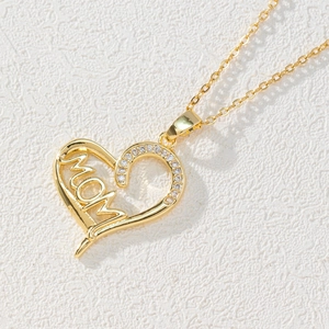 Macro detail of gold-plated heart pendant with MOM engraving and white zircon inlay