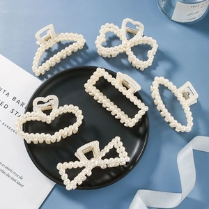 Close-up of pearl-encrusted hair claw clips in heart, bow, and geometric shapes