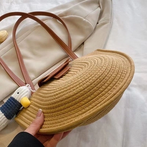 Handmade straw shoulder bag with leather straps and a cute duck charm for summer vacation