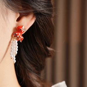 Detail of red enamel koi earring with white pearl tassels on a model for a vintage look