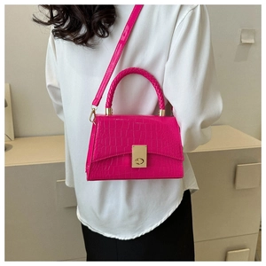 Detail view of pink crocodile pattern handbag with golden twist lock on a shoulder strap