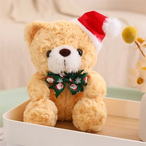 Close-up of a brown teddy bear wearing a red Santa hat and a festive green bow tie