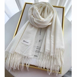 Detail of cream white knit cashmere scarf with soft tassel edges and woven brand label