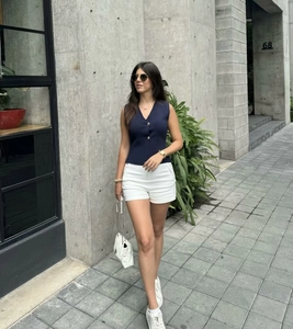 Détail d'un haut en tricot sans manches à col en V bleu marine avec un short blanc
