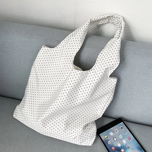 Polka dot canvas tote bag on a grey sofa next to a tablet for size reference