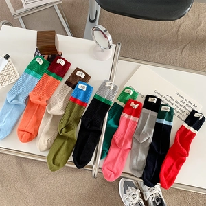 Flat lay of colorful patchwork crew socks with fabric labels on a minimalist white table