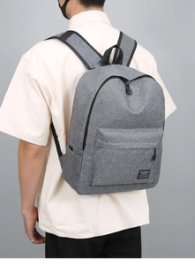 Rear view of model wearing a grey durable travel backpack with large front pocket