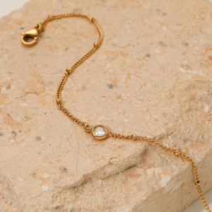 Elegant gold stainless steel anklet with zircon pendant on natural stone surface