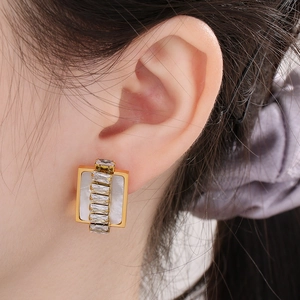 Detail showing gold titanium earrings with rectangular stones and zircon on model ear