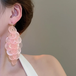 Close-up of long layered pink shell tassel earrings worn by a model for resort style