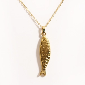 Macro detail of golden fish-shaped pendant showing intricate scale texture and polished finish