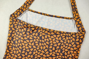 Detail of halter neck design with vibrant yellow oak leaf print on dark knit fabric