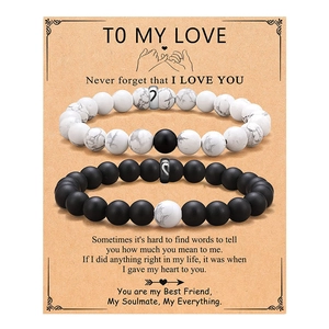 Detailed view of couple beaded bracelets with matching heart charms on a kraft gift card