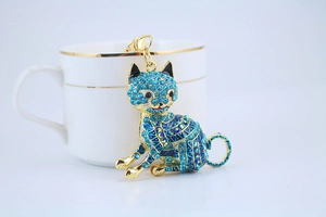 Detailed view of a golden sitting cat keychain inlaid with vibrant blue rhinestones