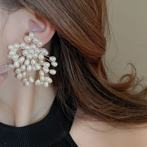 Macro detail of elegant handmade pearl flower earrings with gold wire weaving craftsmanship