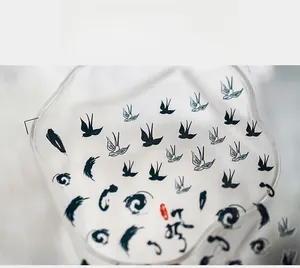 Detail of minimalist ink-style nail stickers featuring black swallows and swirls