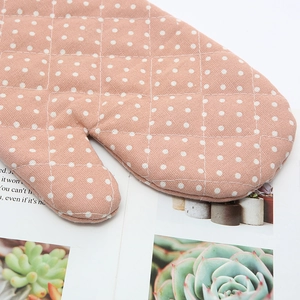Detailed texture of pink cotton pot handle cover with white polka dots and quilted pattern