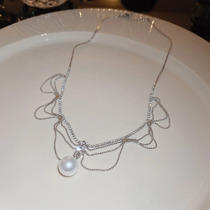 Detailed macro view of the large white pearl and rhinestone lace pendant on a ceramic dish
