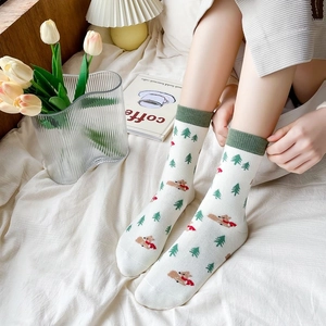 Detail of white cotton socks with green reindeer and Christmas tree embroidery pattern