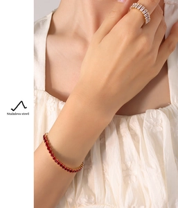 Close-up of stainless steel bracelet with red zircon and white zircon ring on model