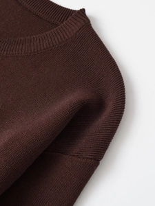 Detailed close-up of dark brown crew neck sweater featuring fine knit texture and stitching