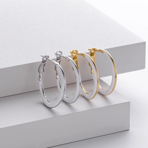Close-up of minimalist 925 silver and gold hoop earrings with white enamel finish