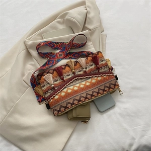 Detail of bohemian woven crossbody bag featuring colorful tassels and ethnic strap