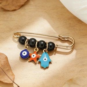 Détail de l'œil bleu et main de hamsa sur une broche dorée avec perles noires