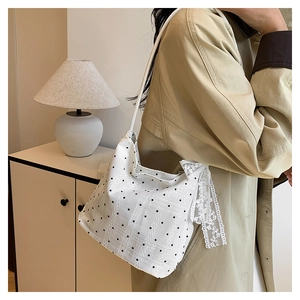 Detail of white polka dot shoulder bag with lace trim shown in a cozy interior setting