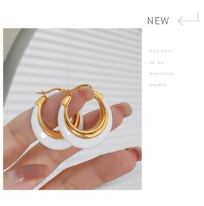 Detail of gold hoop earrings with white enamel finish and secure latch back closure