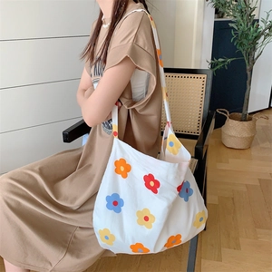 White canvas tote bag with colorful floral print shown in a cozy lifestyle setting