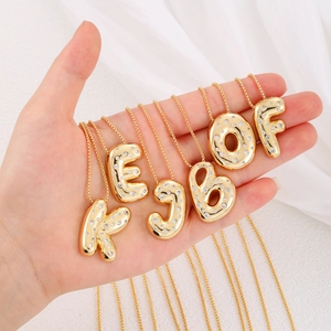 Golden chunky 26 letters necklace pendant with zircon inlays for women on white fabric