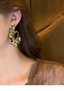 Gros plan sur les boucles d'oreilles cœur léopard avec bordure dorée pour un style rétro