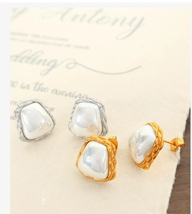 Close-up of vintage geometric earrings with woven metal edges and pearl-like inlay