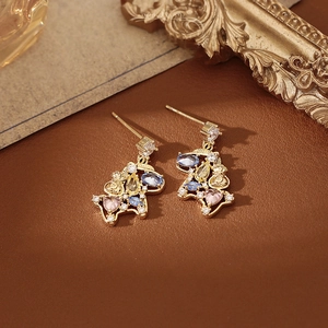 Golden horse pendant earrings with colorful gemstones on a vintage leather surface