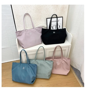 Five assorted colors of large nylon tote bags displayed on a modern white shelf