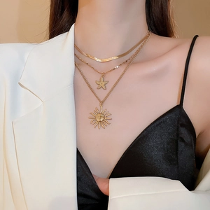 Detailed view of layered gold starfish and sun pendants on a three-tier necklace set