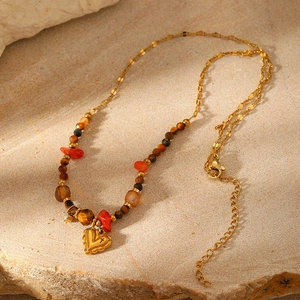Close-up of bohemian gold heart pendant with colorful natural stone beads on a rock