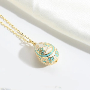 Detail showing white egg pendant with blue enamel flowers and gold chain