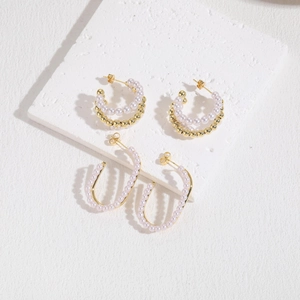 Macro shot of French luxury C-shaped pearl earrings with gold plating and fine detail
