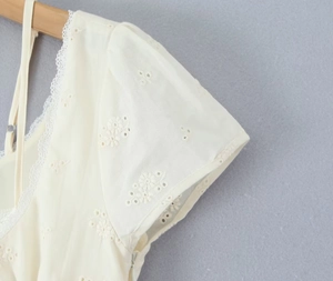 Detail of puffed sleeves and hollow lace embroidery on a cream short dress for women