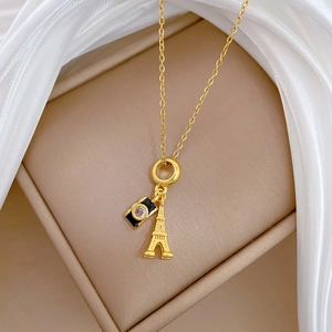 Detailed close-up of camera and Eiffel Tower charms on a gold titanium steel necklace